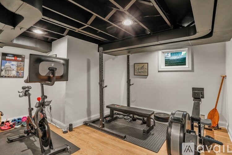 A home gym with a variety of equipment including a treadmill, rowing machine, and weights.