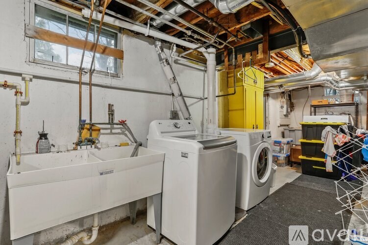 A laundry room with a washer and dryer, a sink, and a window.
