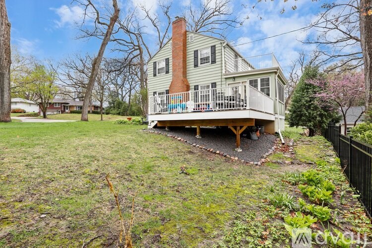 A house with a green lawn and a tree with pink flowers.