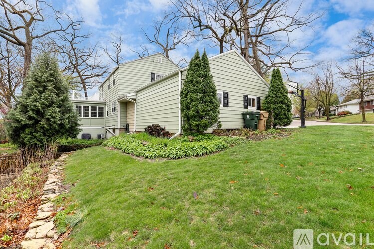 A house with a green lawn and trees in the background.