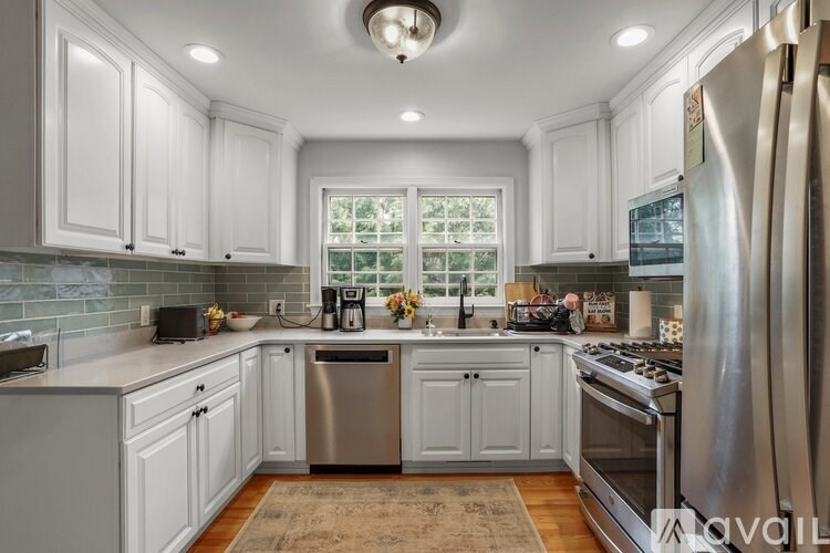 A kitchen with white cabinets and a stainless steel refrigerator.