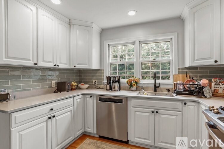 A kitchen with white cabinets and a window.
