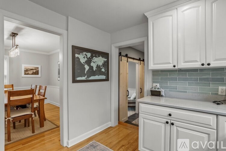 A kitchen with white cabinets and a world map on the wall.