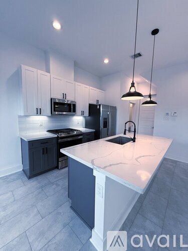A modern kitchen with a marble countertop and dark cabinets.