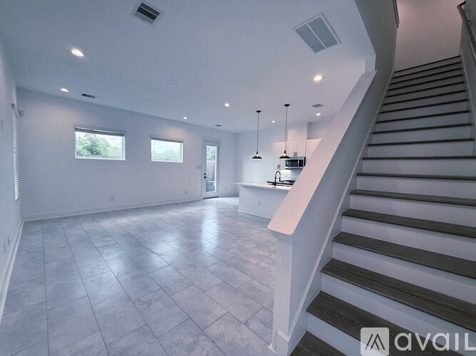 A spacious room with a staircase leading to the upper level.