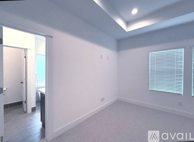 A room with a window and a door leading to a balcony.