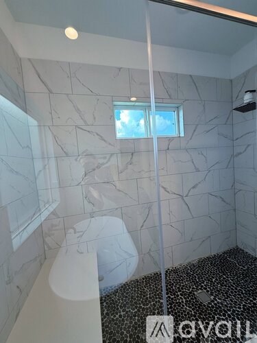 A bathroom with a marble wall and a shower with a glass door.