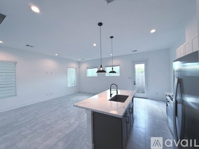 A modern kitchen with a large island and pendant lights.