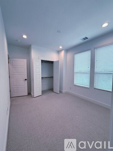 A room with a carpeted floor and a window with blinds.