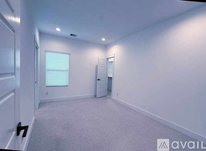 A spacious room with a carpeted floor and white walls.