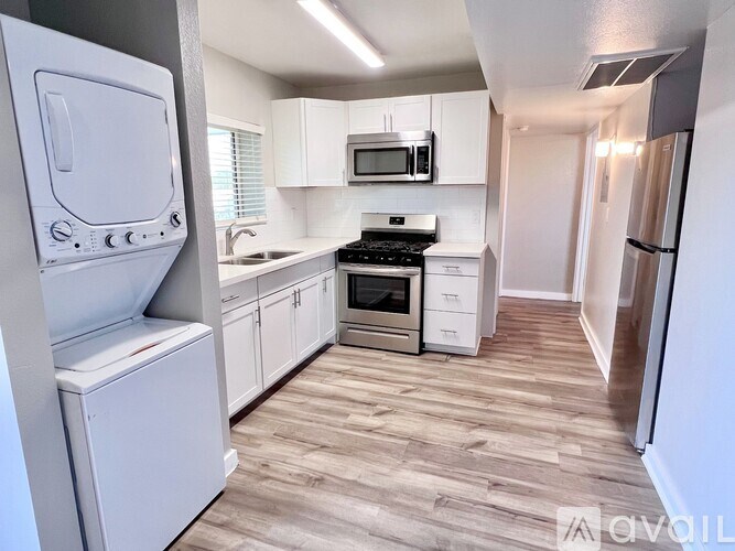 A kitchen with white appliances and wooden floors.