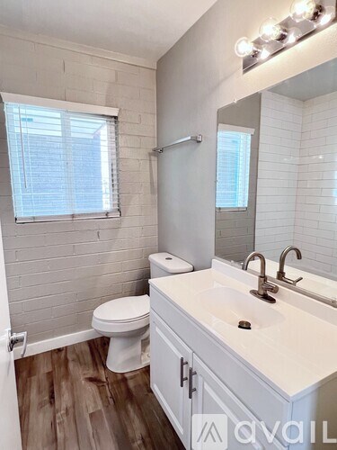 A white bathroom with a toilet, sink, and mirror.