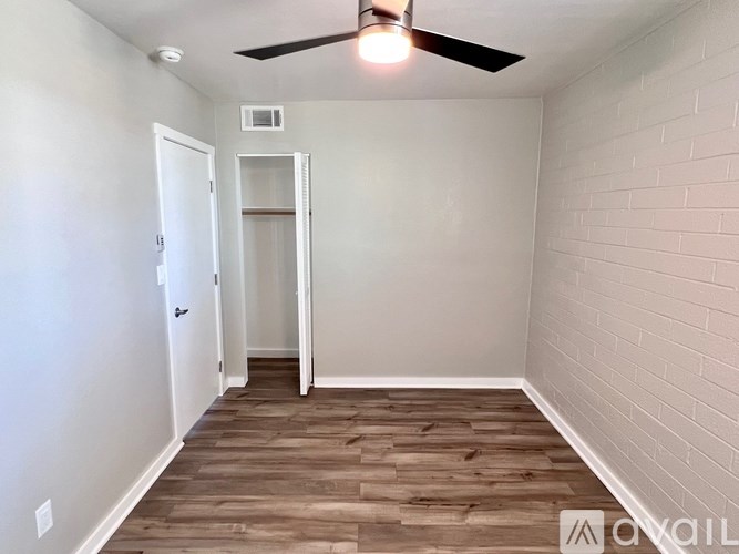 A room with a ceiling fan and wooden flooring.
