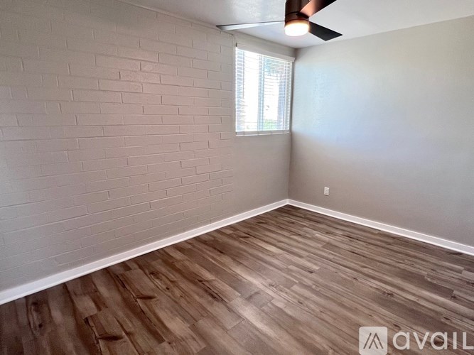 A room with wooden flooring and a window with blinds.