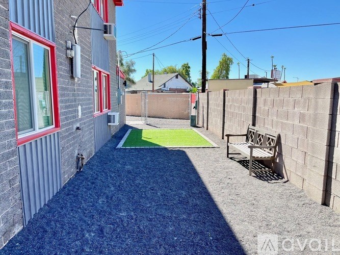 A small backyard with a blue carpet and a wooden bench.