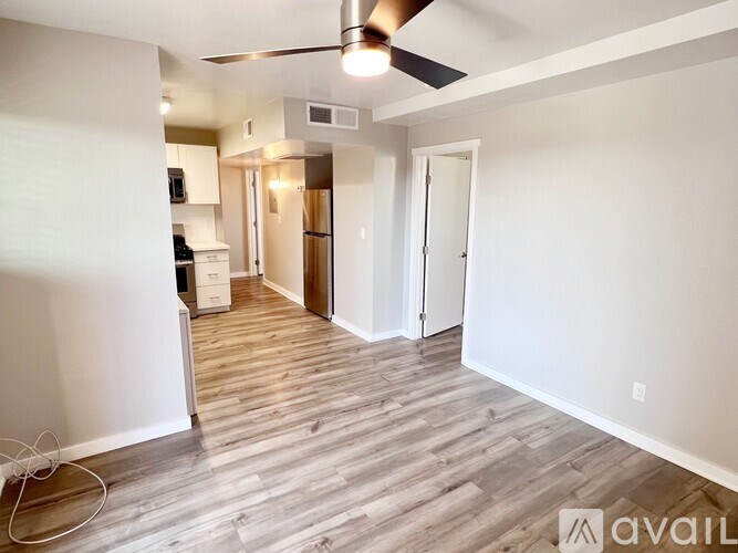 A room with a fan and wooden flooring.