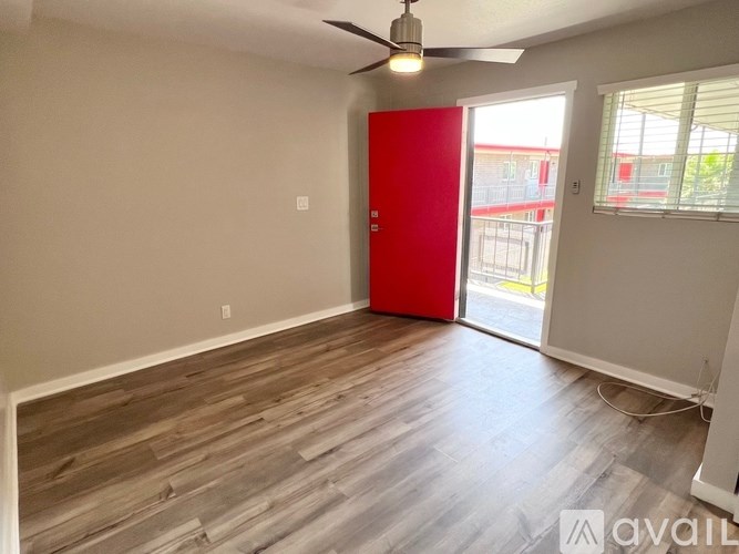 A room with a red door and a ceiling fan.