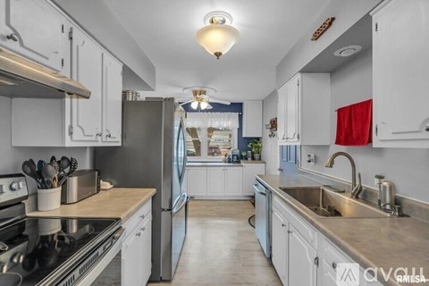 A kitchen with white cabinets and a blue refrigerator.