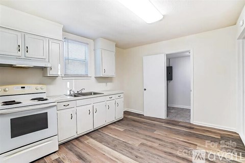A kitchen with white cabinets and a wood floor.