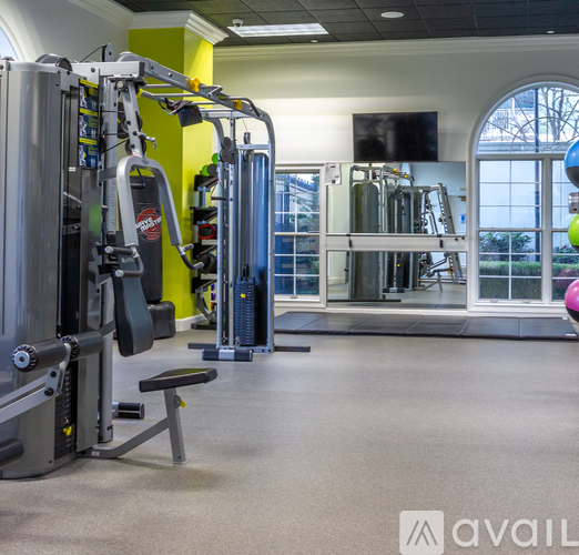A gym with a variety of equipment including a weight bench, a leg press machine, and a cable machine.