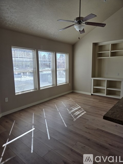 A room with a ceiling fan and a large window.