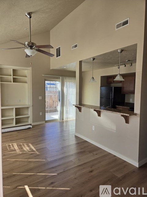 A spacious living room with a ceiling fan and a sliding glass door leading to a balcony.
