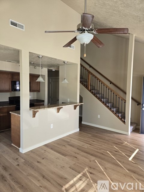 A living room with a staircase and a ceiling fan.