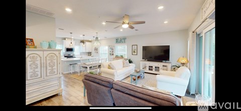 A living room with a brown couch and a white chair.