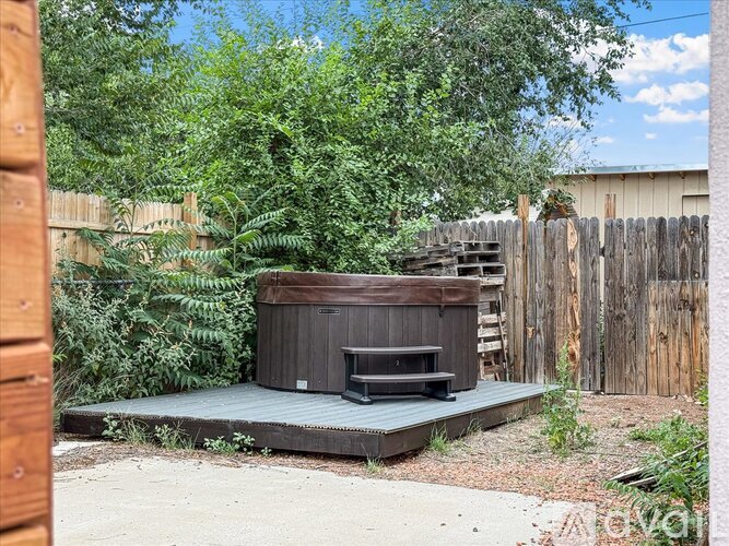 A hot tub is surrounded by a wooden deck and greenery.