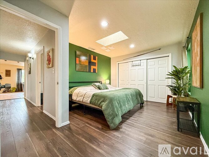 A bedroom with a green wall and a bed with a green blanket.