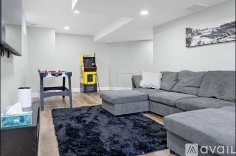 A living room with a grey couch and a black rug.