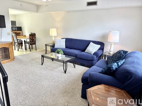A living room with a blue couch and a glass coffee table.