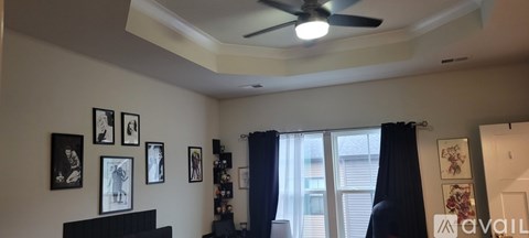 A living room with a black couch and pictures on the wall.