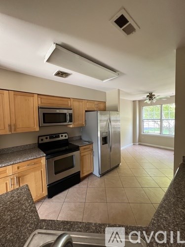 A kitchen with wooden cabinets and a stainless steel refrigerator.