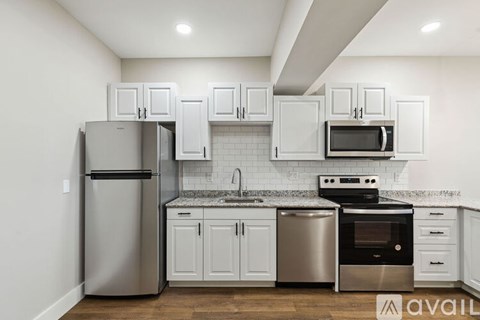 A kitchen with white cabinets and a stainless steel refrigerator.