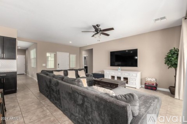 A living room with a grey couch and a television on the wall.
