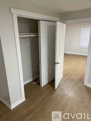 A room with a white door and a wooden floor.