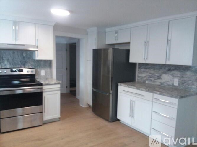 A kitchen with white cabinets and a marble countertop.