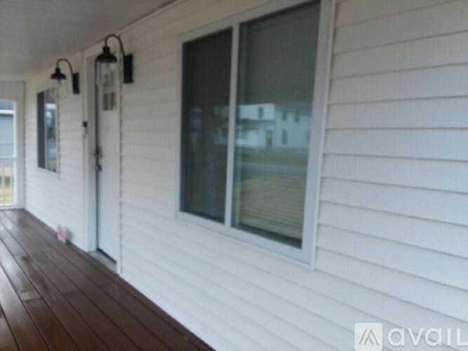 A white house with a wooden deck and a window.