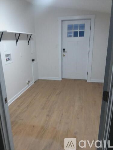 A room with a white door and wooden floor.