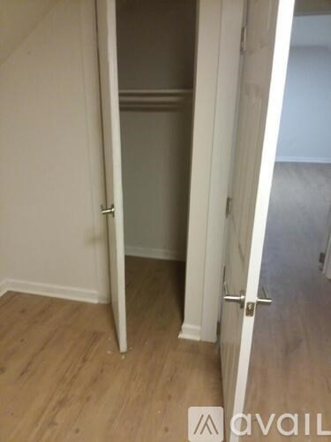 A room with a white door and a wooden floor.