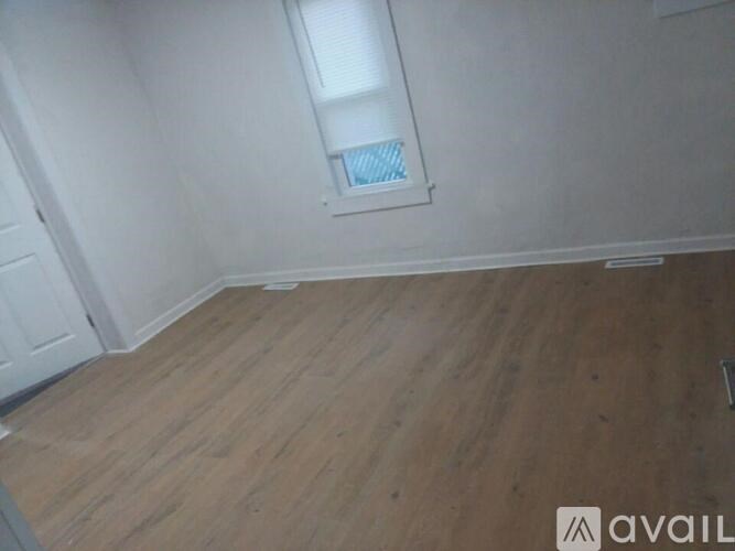 A room with wooden flooring and a window with blinds.
