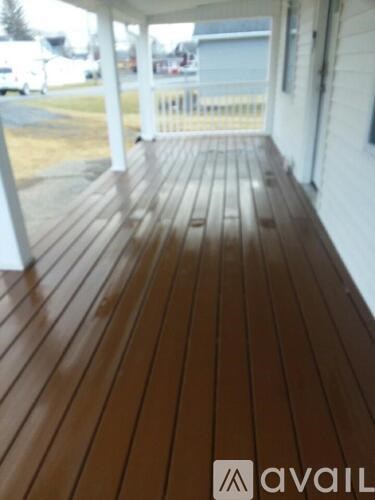 A wooden deck with a white railing and a white wall.