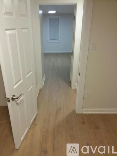 A hallway with a white door and wooden flooring.