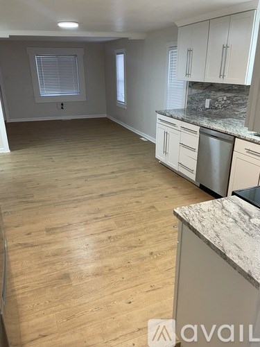A kitchen with wooden floors and white cabinets.