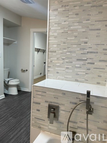 A bathroom with a toilet, sink, and a wall of tiles.