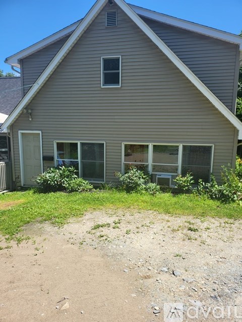 A house with a grey siding and a white door is shown.