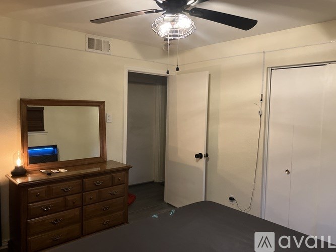A bedroom with a dresser and mirror, a ceiling fan, and a bed.