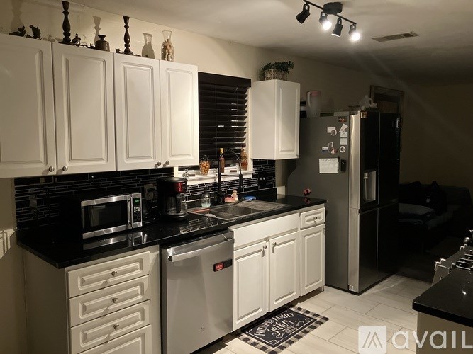 A kitchen with white cabinets and black countertops.