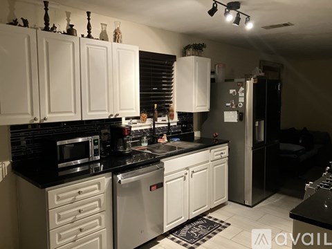 A kitchen with white cabinets and black countertops.